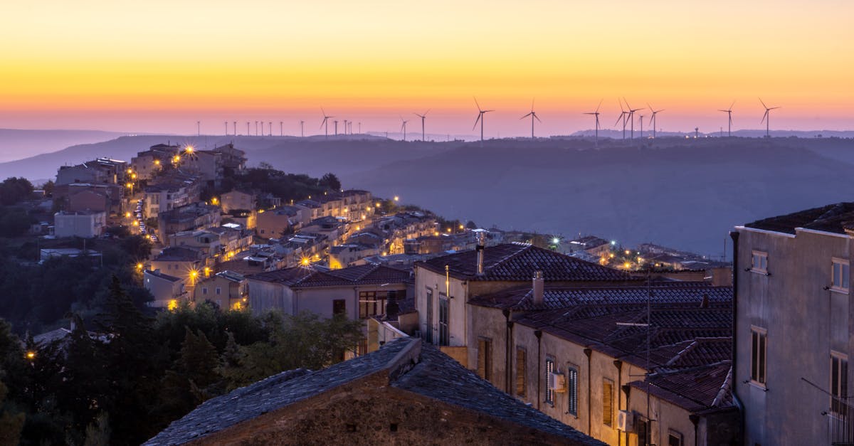 Beautiful view of a town at sunset with wind turbines on the horizon, creating a serene and eco-friendly atmosphere.