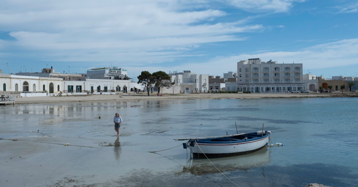 Peaceful seaside view with a moored boat and coastal buildings in Salento, Italy.