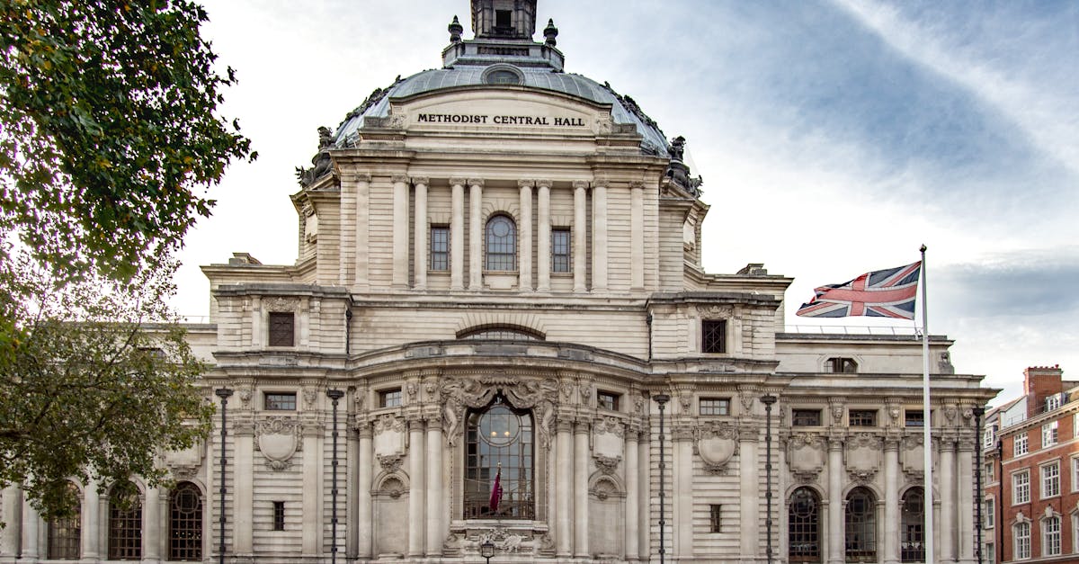 Historic Methodist Central Hall in London with British flag and sky backdrop.