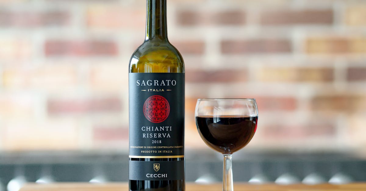 Sagrato Chianti Riserva 2018 wine bottle and glass on wooden surface with blurred brick background.