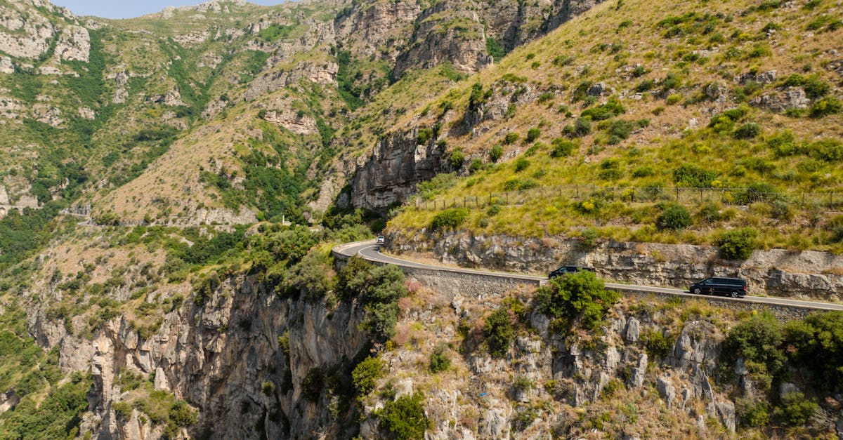Breathtaking view of a winding road along steep cliffs with lush greenery, ideal for nature exploration.