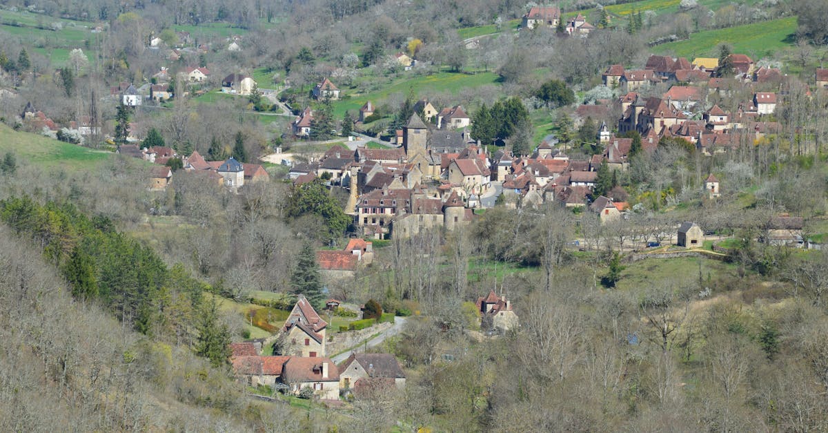 Aerial view of a picturesque European village surrounded by lush greenery and hilly terrain.