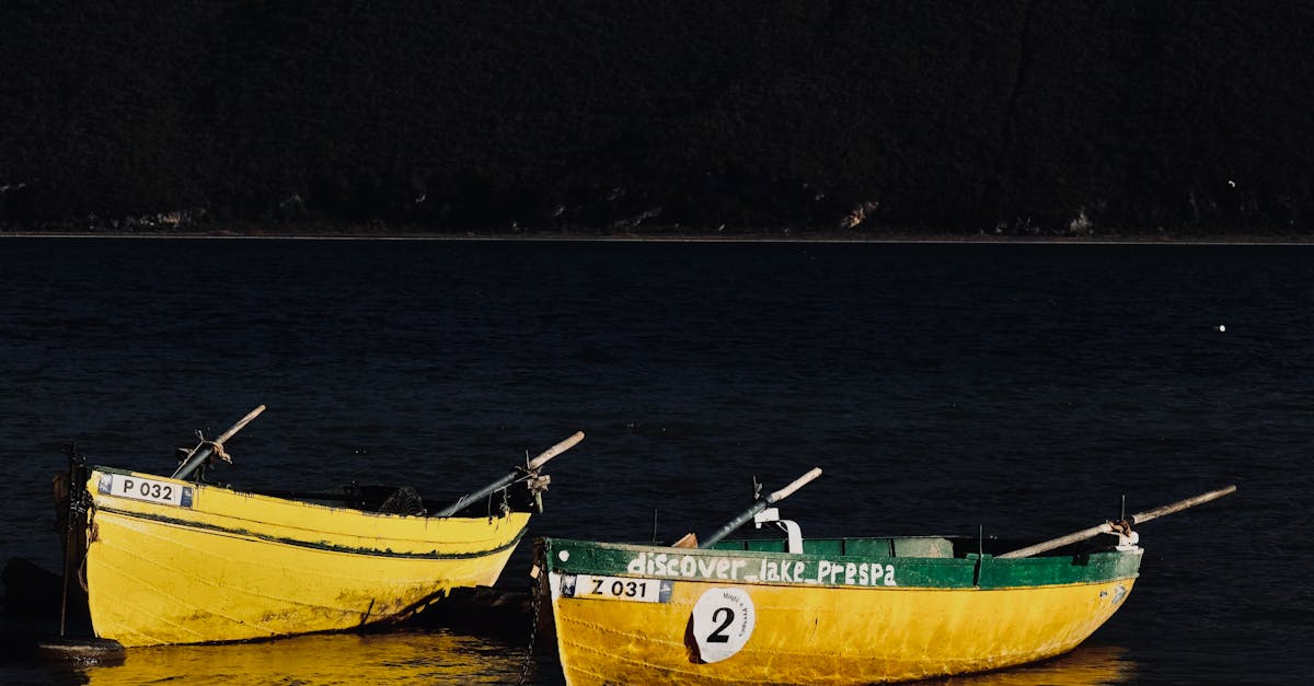Two yellow boats resting on Lake Prespa's shore during dusk, reflecting in the calm water.