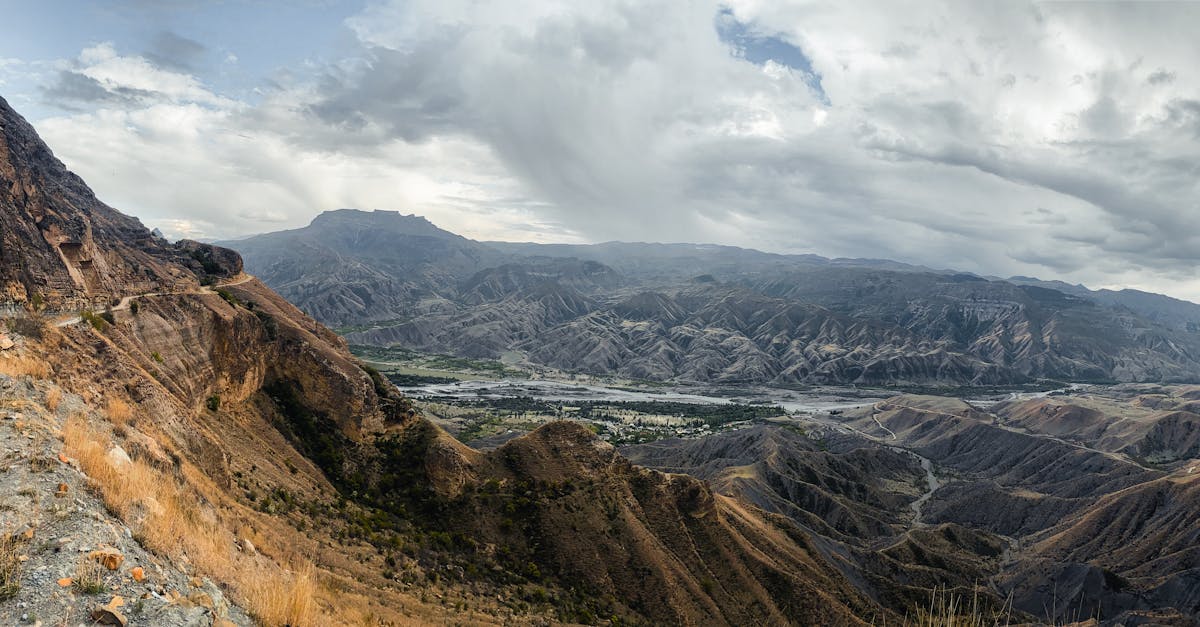 Stunning aerial panorama of rocky mountains in Dagestan, Russia with a dramatic cloudy sky.