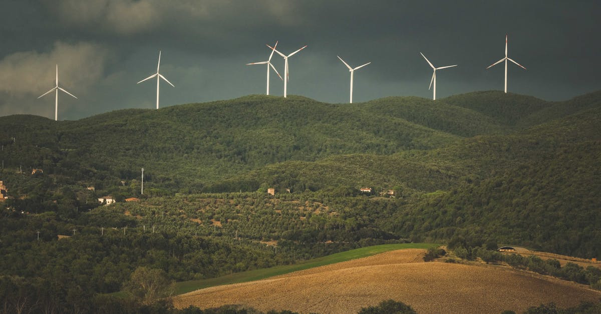 A picturesque view of wind turbines on green hills under dramatic clouds, showcasing sustainable energy.