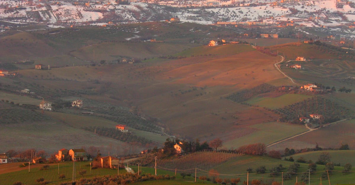 Scenic aerial landscape of rolling hills and fields at sunset in Italy.