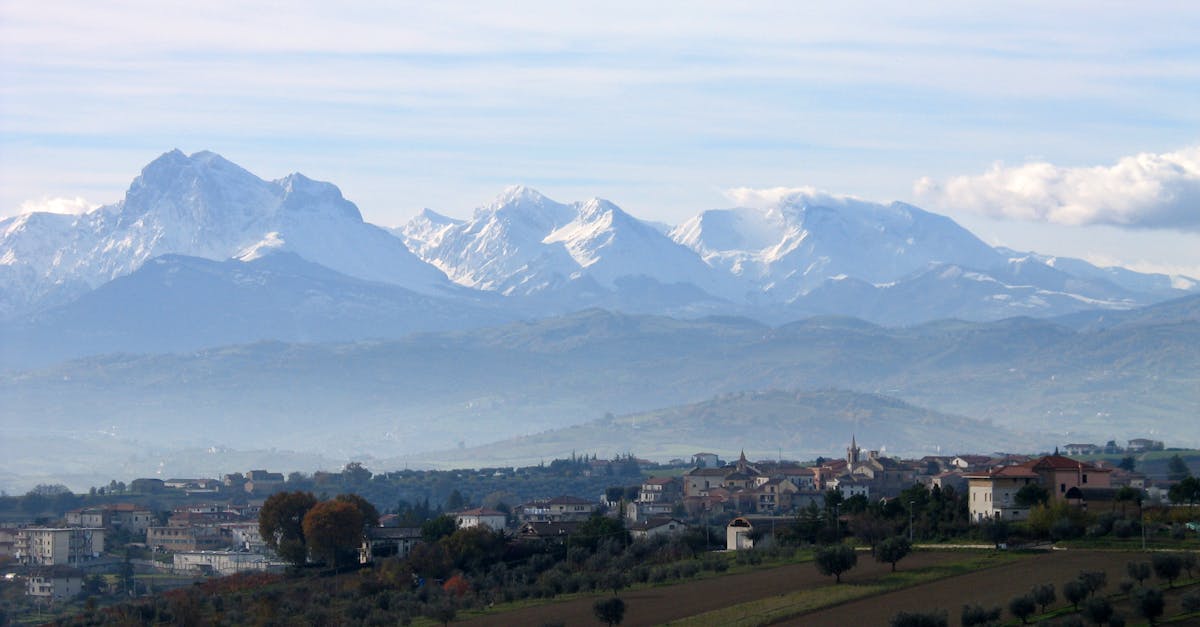 Breathtaking view of snow-capped Apennine mountains with a quaint Italian village in the foreground.