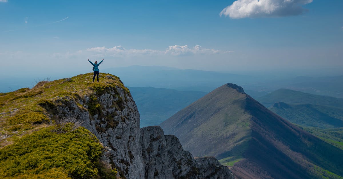 A person celebrating victory atop a mountain peak in Serbia with breathtaking views.