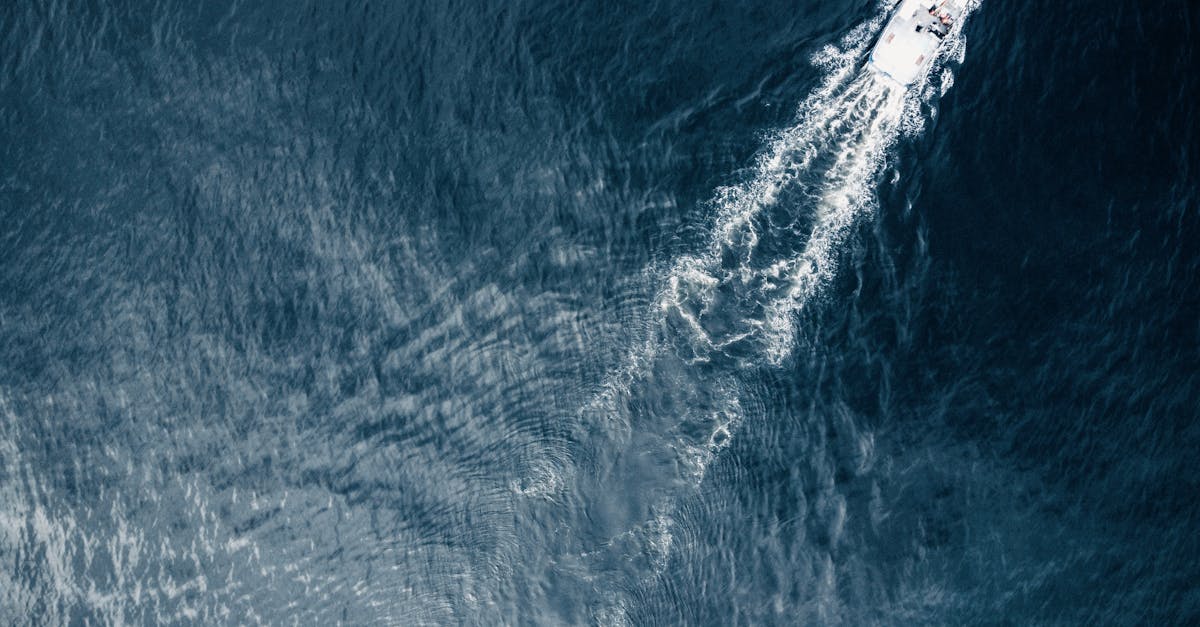 A motorboat speeding through open water leaving a trail behind, captured from above.