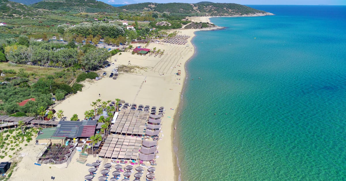 Drone shot of a serene beach with sunbeds and clear blue water, perfect for a summer getaway.