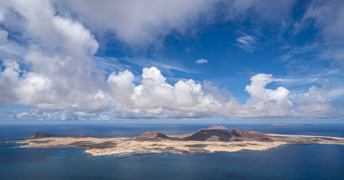 Breathtaking aerial view of La Graciosa Island with vibrant blue skies and fluffy clouds.