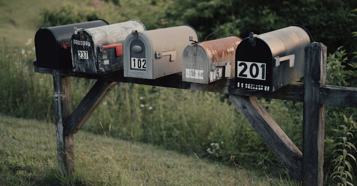 Close-up of rusty, rural mailboxes on a wooden frame in a lush summer meadow in Suches, GA.