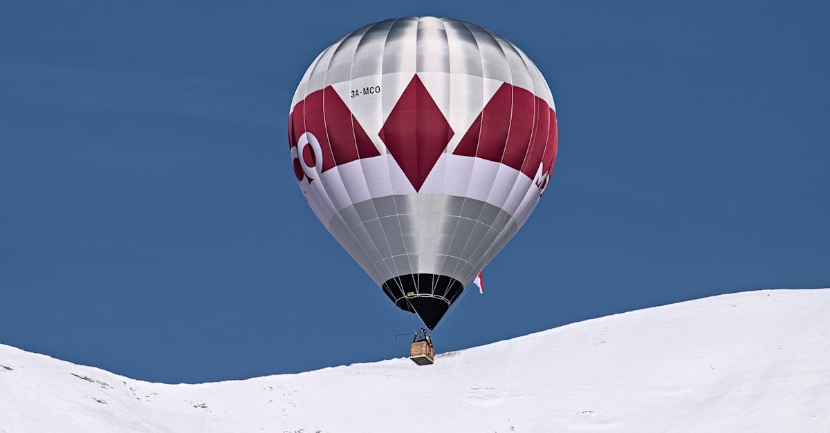 A vibrant hot air balloon flying over the snowy peaks of Château-d’Œx, Switzerland.