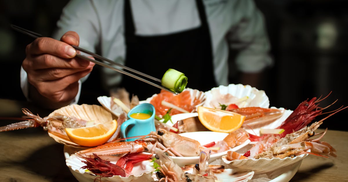 A chef elegantly presents a seafood platter with chopsticks. Fresh shrimps and lemons.