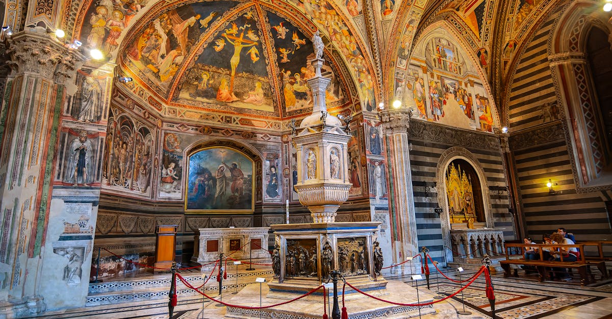 Explore the ornate Siena Baptistery interior adorned with stunning frescoes and religious art.