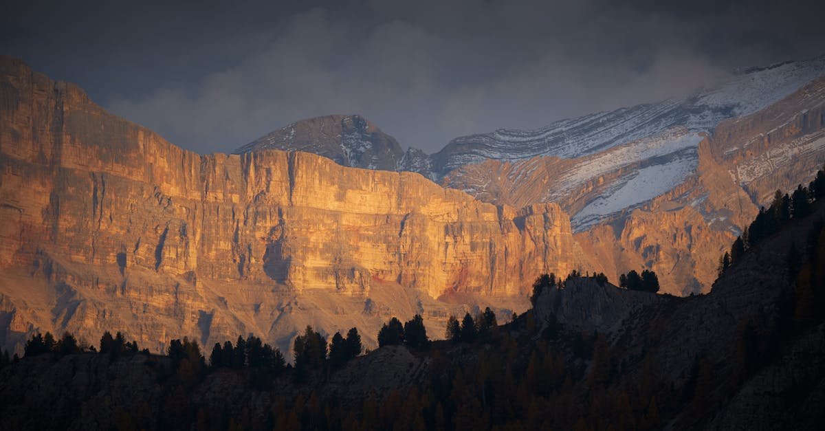 Dramatic view of snowcapped cliffs sunlit at sunset, creating a striking landscape scene.