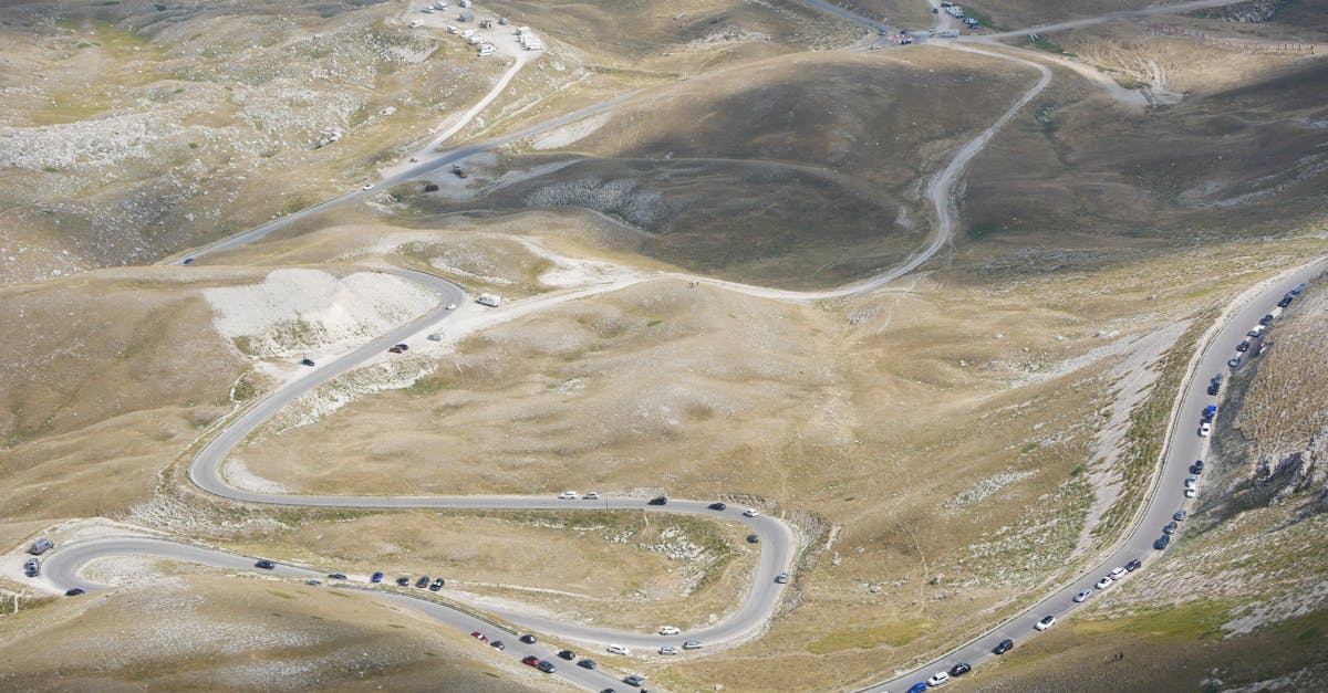 Aerial view of a winding mountain road with cars in L'Aquila, Abruzzo, Italy, showcasing stunning landscapes.