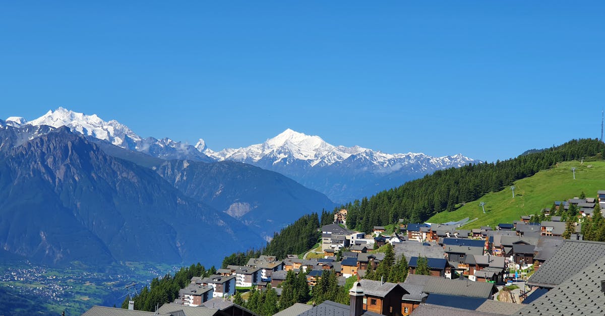 Panoramic view of Bettmeralp village with majestic Swiss Alps in the background, under a clear blue sky.