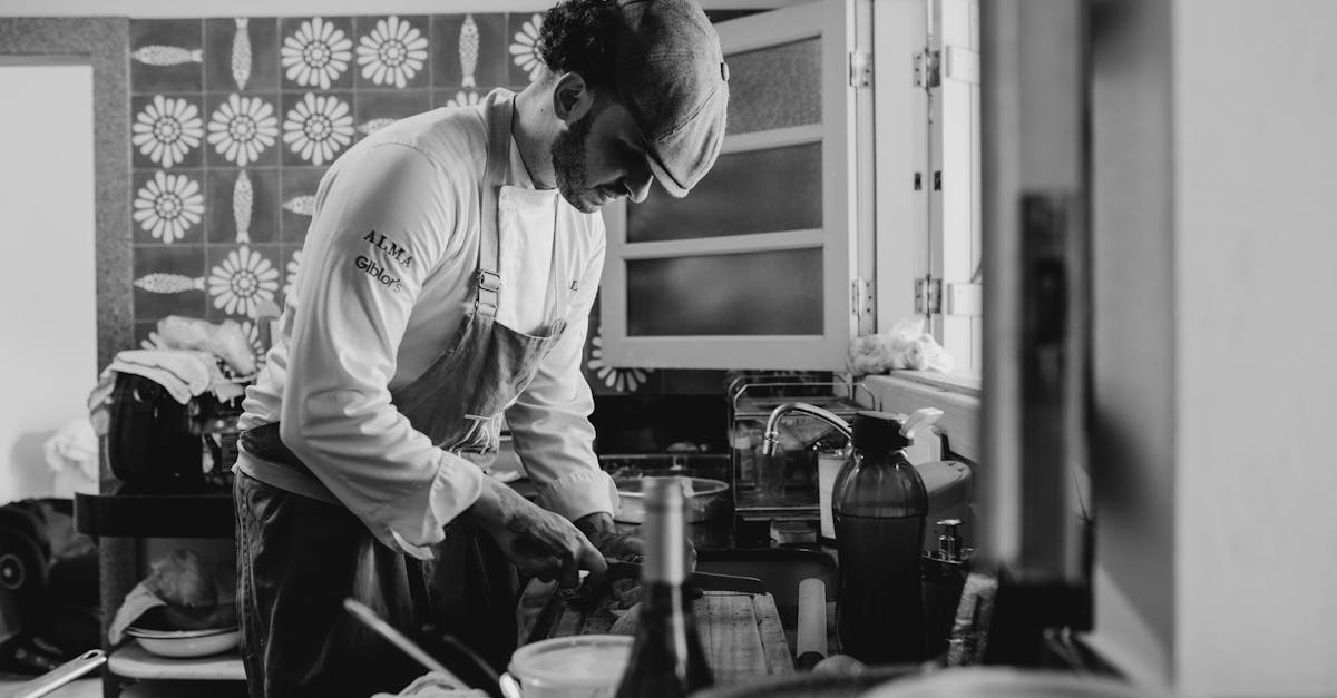 Chef in a kitchen preparing a meal, captured in black and white for a classic feel.