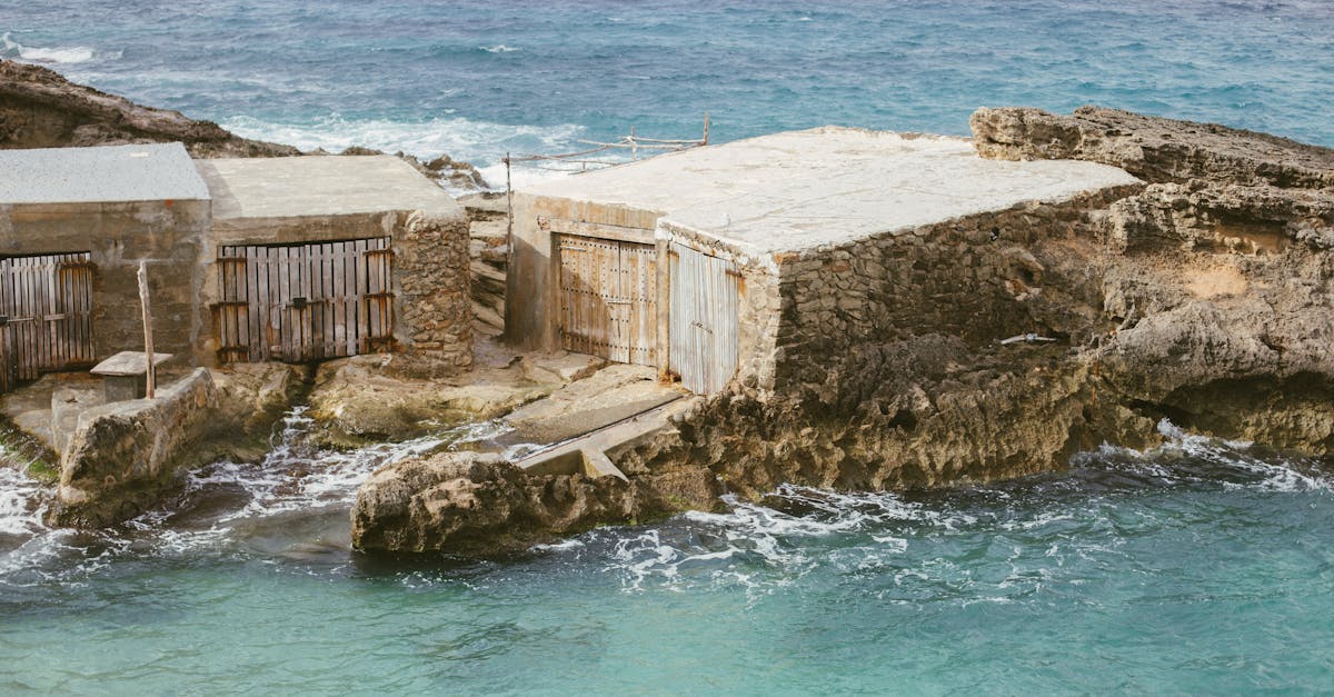 Weathered fishermen's sheds by the azure sea in Ibiza, Spain, showcasing rustic coastal charm.