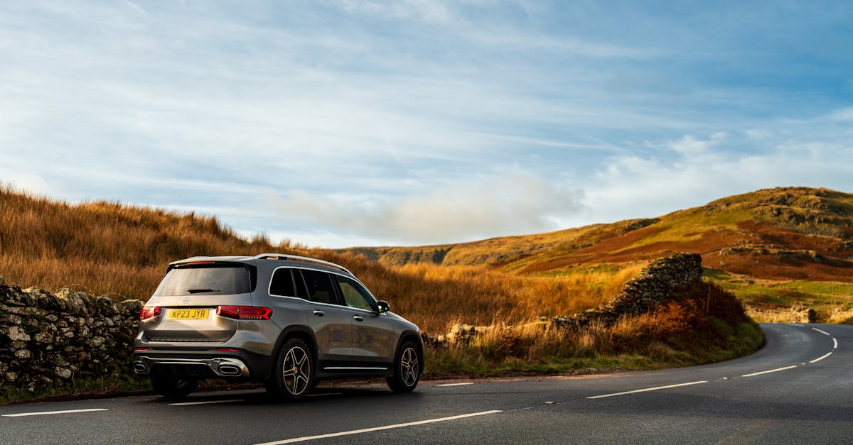 Sporty SUV navigating a winding road in a picturesque countryside setting under a clear blue sky.