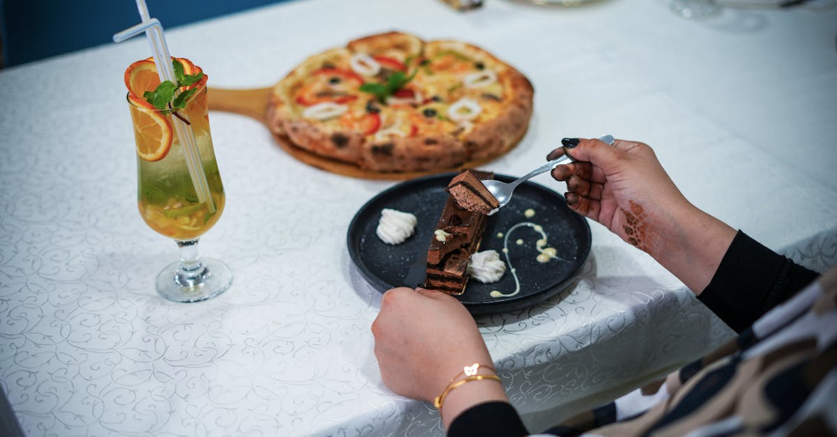 A table setting featuring a fresh pizza, chocolate dessert, and a refreshing cocktail. Ideal for dining themes.