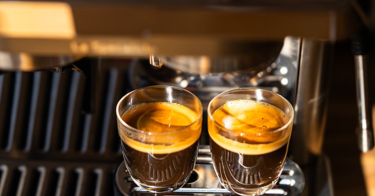 Two freshly brewed espresso shots under a modern coffee machine, highlighting crema and rich aroma.