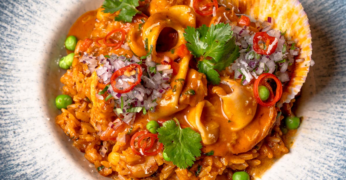 Mouth-watering seafood risotto garnished with chili and cilantro, perfect for gourmet enthusiasts.