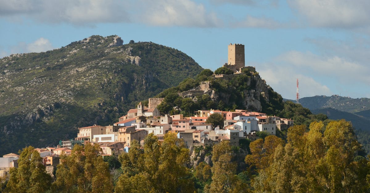 Scenic view of an Italian hilltop village with ancient tower and lush greenery under a clear sky.