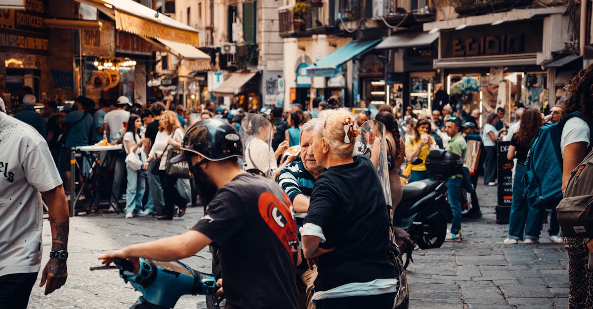 Vibrant European street market bustling with diverse people and scooters in daytime setting.