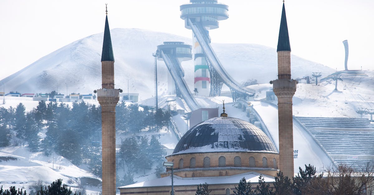 A snowy view of the mosque in Erzurum, Türkiye, with ski jumps in the backdrop, capturing winter's serene beauty.