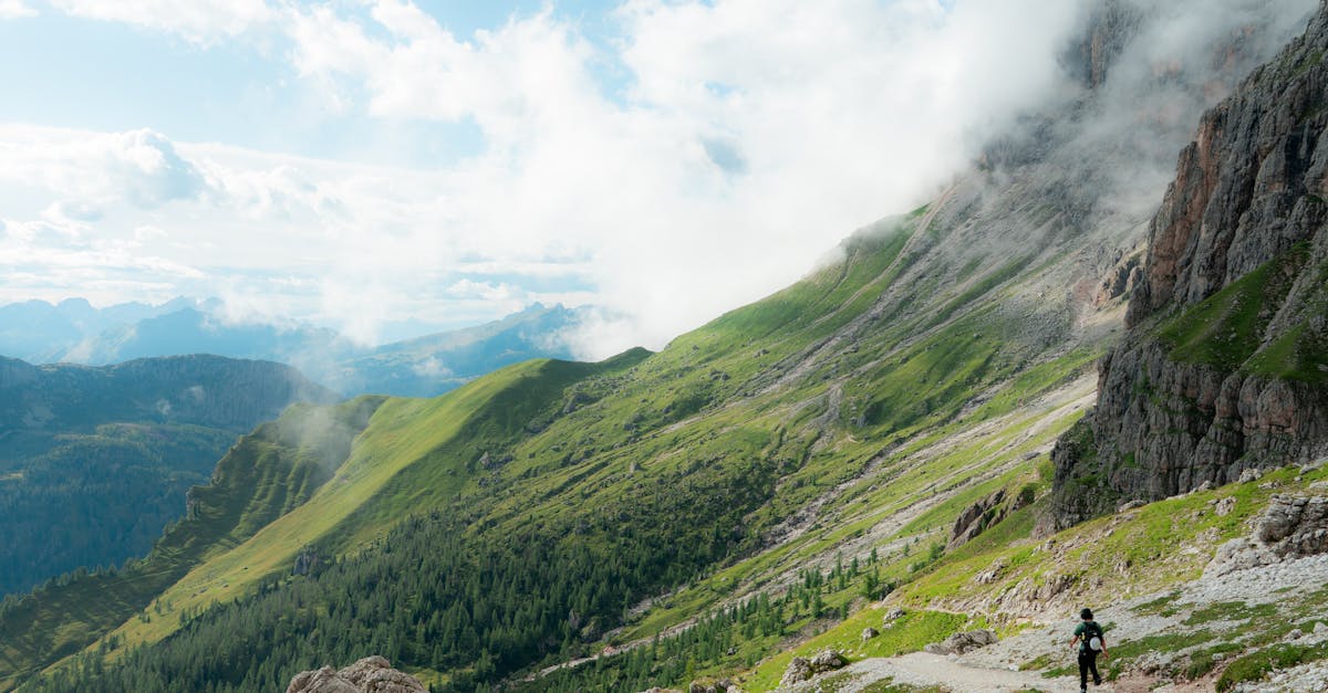 A hiker explores the lush trails of the Dolomite mountains surrounded by clouds.