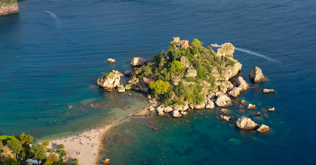 A breathtaking aerial shot of Isola Bella in Sicily, Italy, showcasing its vibrant greenery and crystal-clear blue waters.