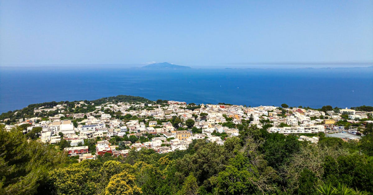 Stunning panoramic view of Capri island's whitewashed buildings and lush greenery against the deep blue Tyrrhenian Sea.
