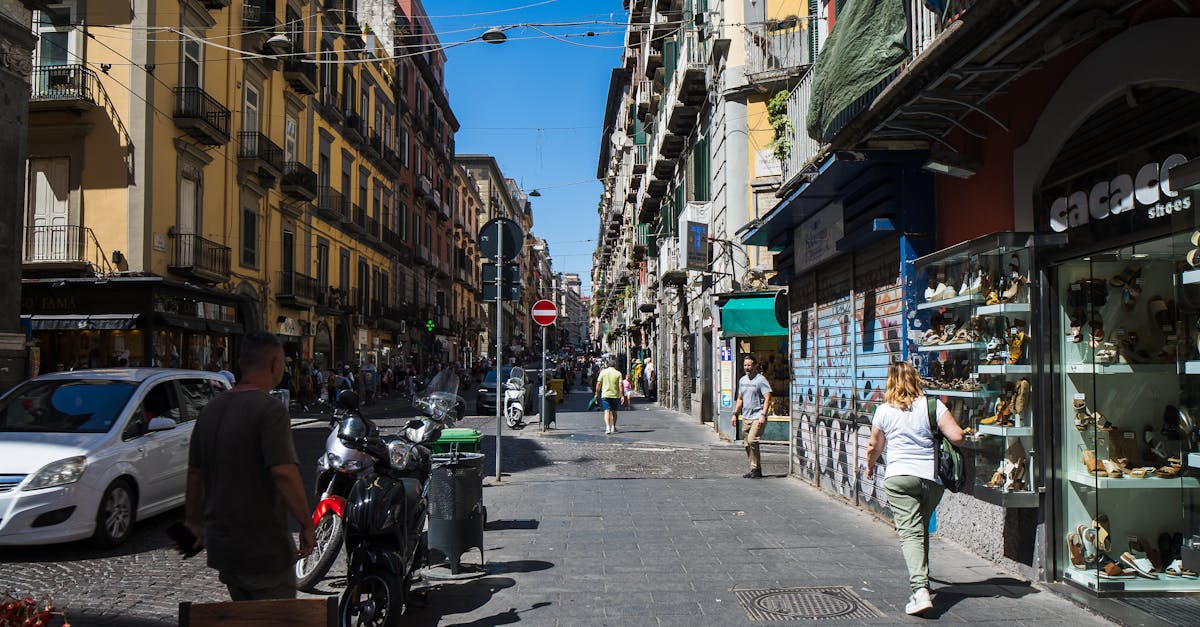 Bustling street view in Naples with shops and pedestrians on a sunny day.