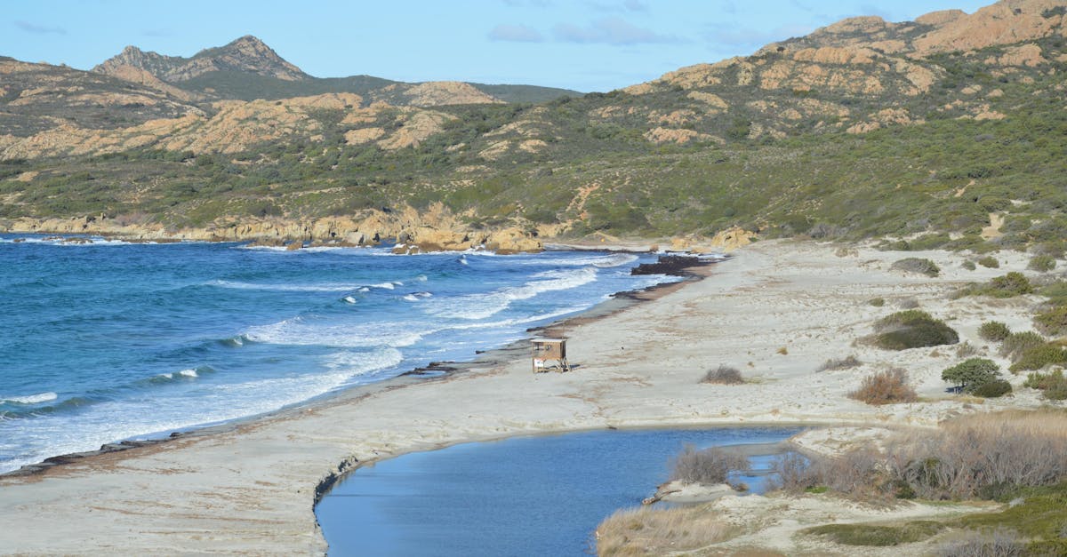 Beautiful beach scene on Corsica's coastline with waves and rugged terrain.
