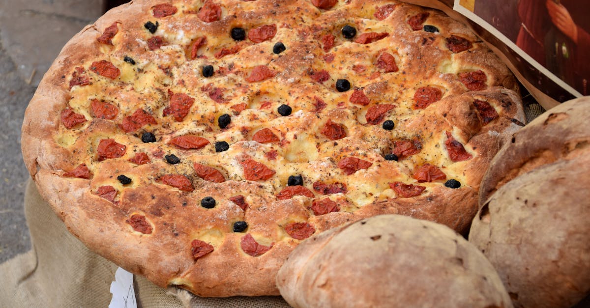 Freshly baked Italian focaccia topped with cherry tomatoes and black olives, showcasing rustic Mediterranean cuisine.