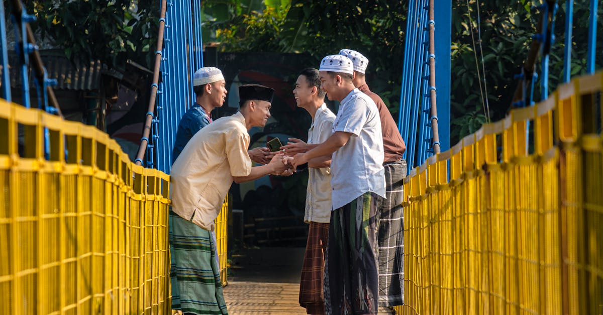 Men in traditional attire greet each other warmly on a suspension bridge in West Java, Indonesia.