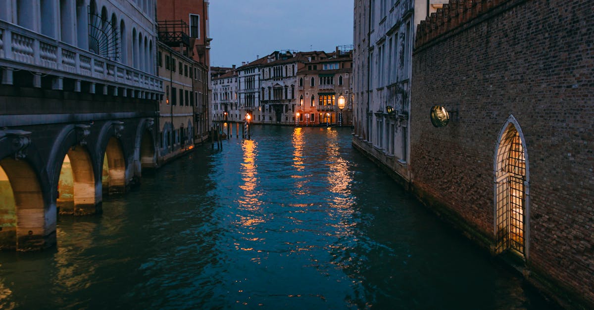 Serene Venetian canal at twilight with charming architecture and warm lights reflecting on water.
