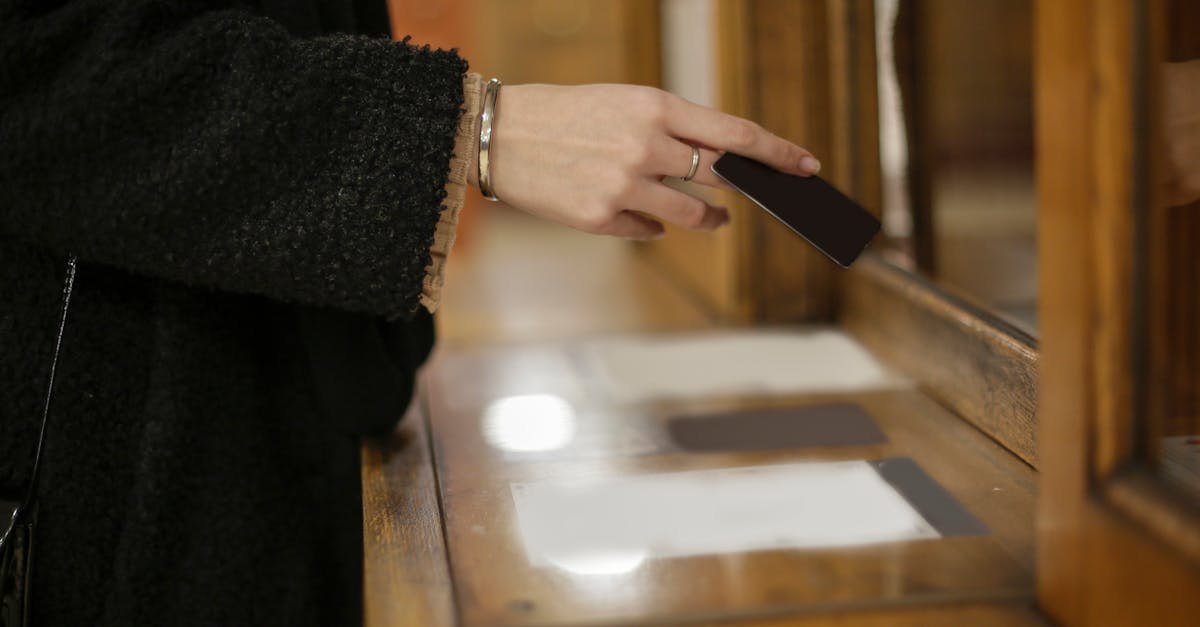Close-up of a woman's hand using a black card for payment at an indoor counter.