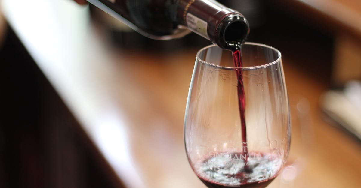 Close-up of red wine being poured into a glass with a selective focus and blurry background.