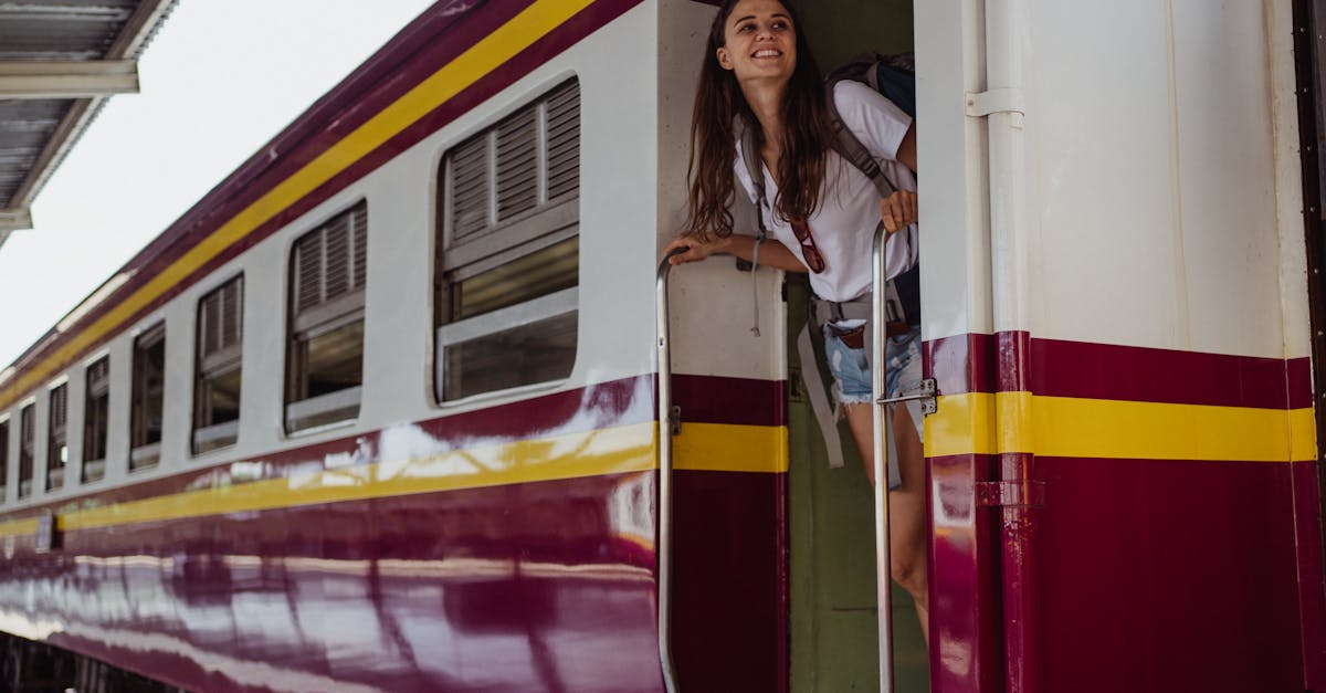 Smiling woman standing at train doorway, appreciating the scenic railway journey.
