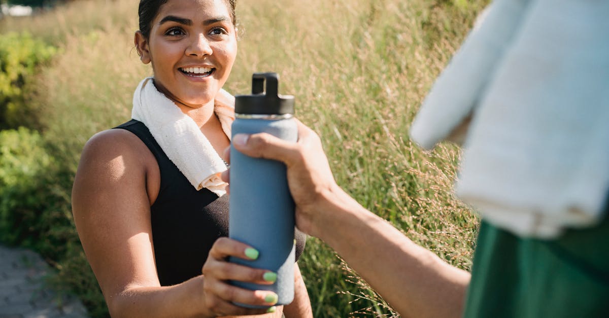 Smiling woman receiving water bottle during outdoor exercise.