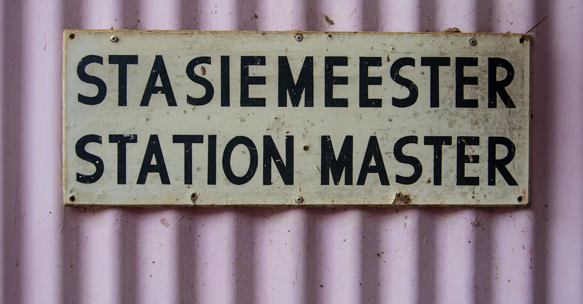 Close-up of a vintage 'Station Master' sign on a corrugated pink wall.