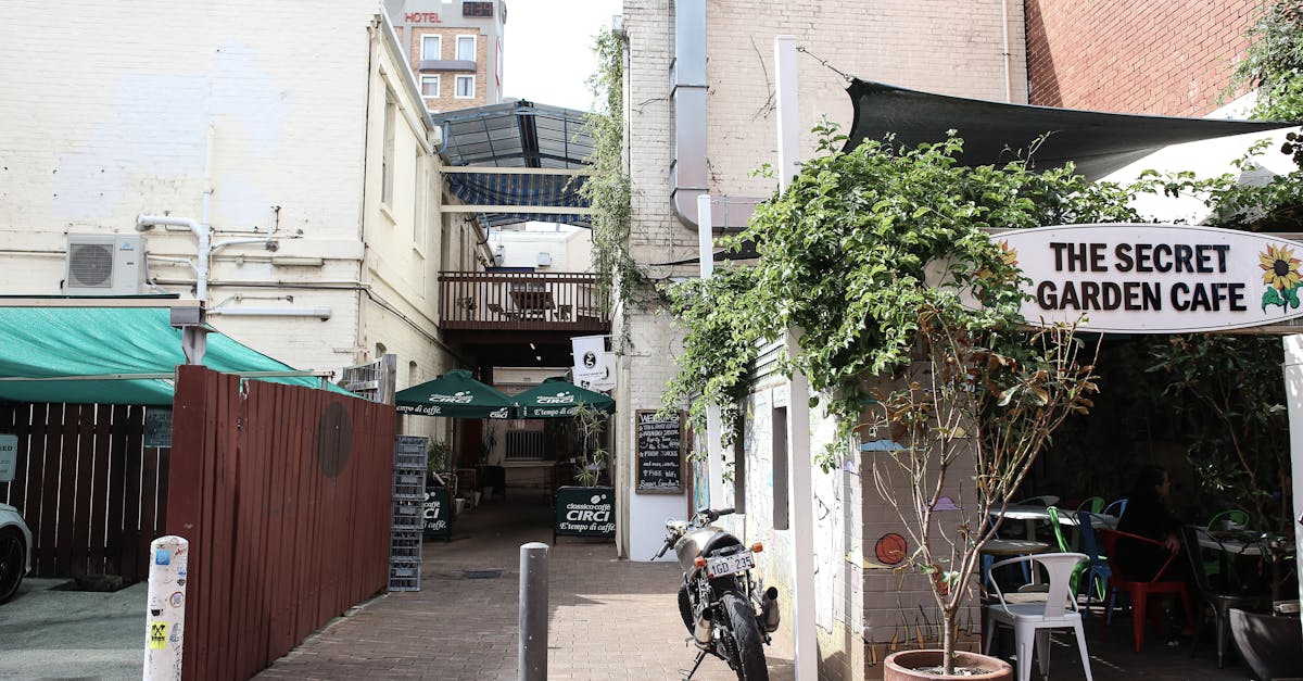 Explore the rustic charm of a hidden cafe in a narrow city alley, complete with greenery and a parked motorcycle.