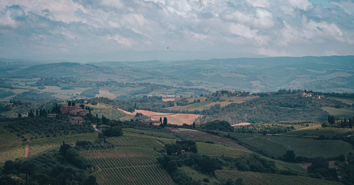 Breathtaking aerial shot of Tuscany's rolling hills and vineyards under a cloudy sky.