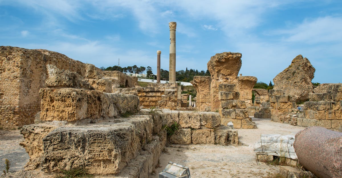 Ruins of aged destroyed stone constructions with rough surface and tower located in Tunisia city in Turkey against cloudy sky