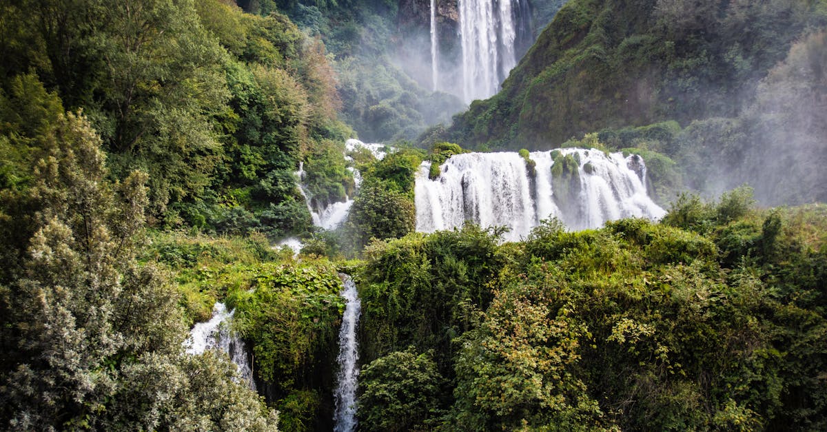 Explore the beauty of cascading waterfalls amidst lush forest greenery, captured in vivid detail.