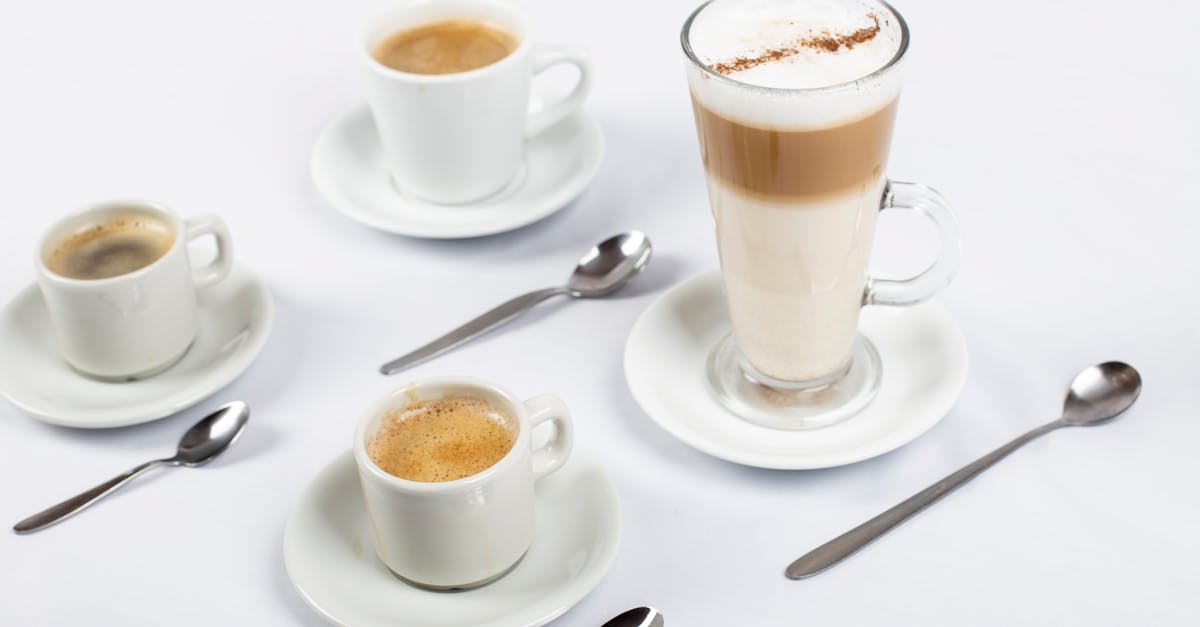 A stylish arrangement of coffee cups, saucers, and teaspoons on a white surface.