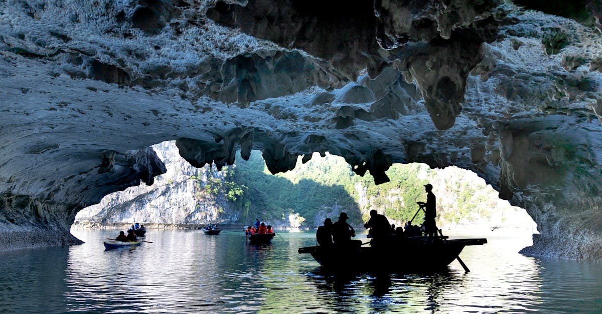 Silhouetted tourists explore a cave on a scenic boat tour, casting reflections in water.